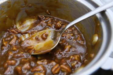 saucepan of pecan caramel with a spoon in the center