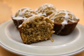 carrot muffin cut in half on a plate with 3 other muffins in the background