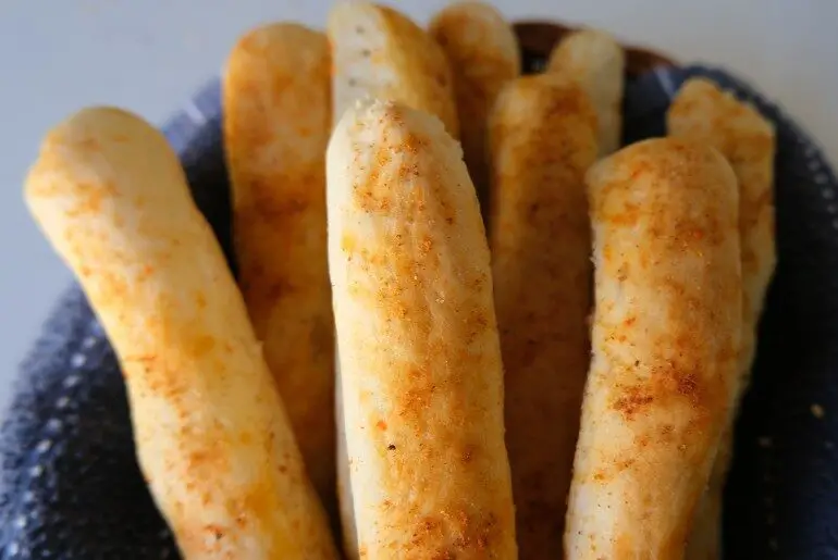 breadsticks in a basket with a blue dishcloth