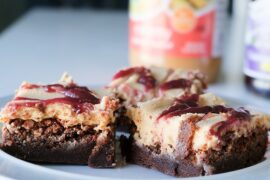 3 brownies arranged on a blue plate with peanut butter and jelly in the background