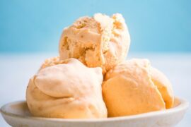 3 scoops of vanilla ice cream in a white dish with a blue background