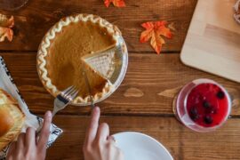 pumpkin pie being cut sitting on a wooden table