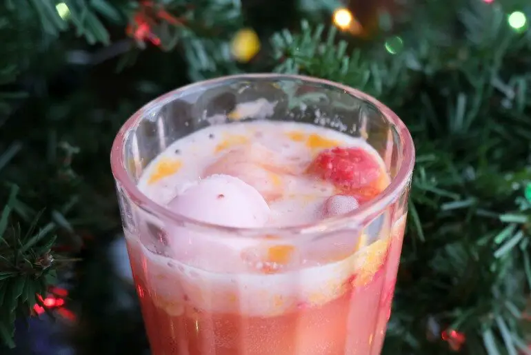 raspberry orange punch in a glass in front of a christmas tree