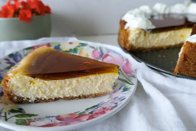 a slice of cheesecake on a floral plate with the rest of the cheesecake on a black plate in the background
